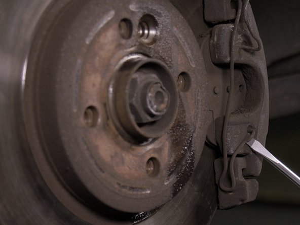 Retirer le ressort antivibration à l'aide d'un tournevis plat, commencer par le haut puis terminer par le bas