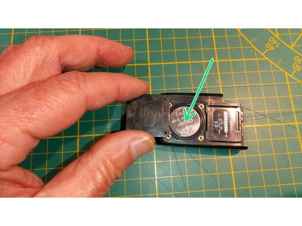 Introduire la nouvelle pile en pressant suivant la direction de la flèche verte