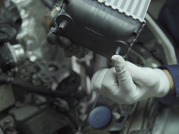 Repérer les deux guides sur le bas du radiateur et leurs logements dans l'emplacement