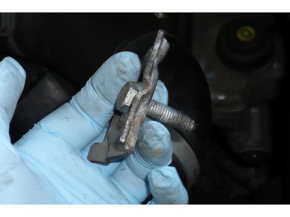 Penser à tenir la vis vers la fin afin qu'elle ne tombe pas dans les entrailles de votre compartiment moteur. A défaut vous devrez partir à la pèche avec un aimant. On voit bien la patte de maintient de la batterie. Notez sa position pour le remontage.