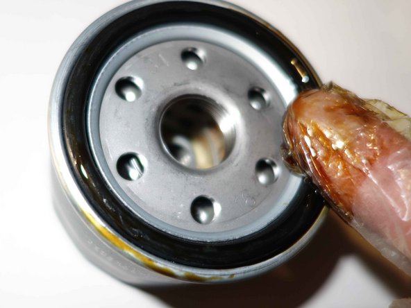 Visser à la main, le filtre neuf à son emplacement, sur le bloc moteur.