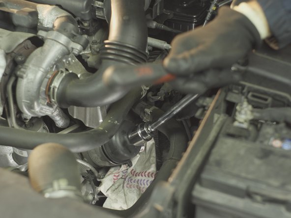 A l'aide d'un cliquet, d'une rallonge longue et d'une douille de 27, desserrer la cloche du filtre à huile