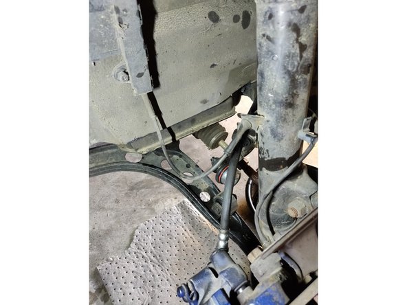 En laissant un peu de flexion sur la durite, mettez l'axe en caoutchouc dans son logement sur l'amortisseur