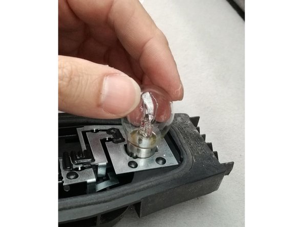 remplacement par la nouvelle ampoule, insérée dans son logement et tournée d'un quart de tour tout en la maintenant enfoncée