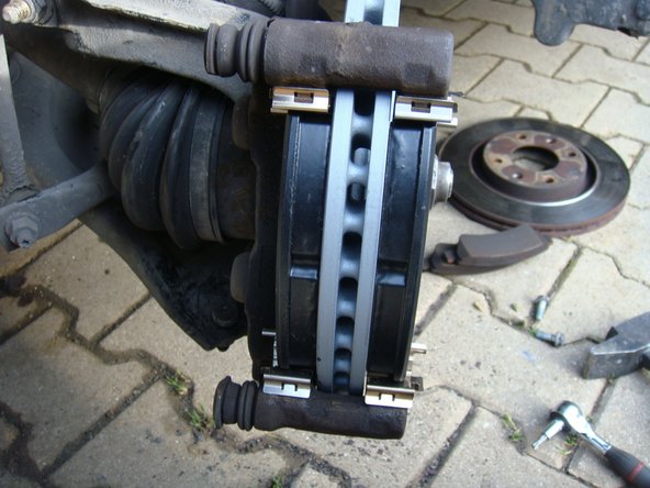 Glisser la nouvelle plaquette sur son ressort en commençant par le bas puis finir en la guidant en haut