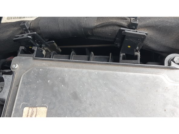 on devisse les 4 vis (8mm) qui maintiennent le calculateur, puis on coulisse tous les clips de maintien des câbles latéraux, et on bascule le tout (cables et calculateur) en arrière