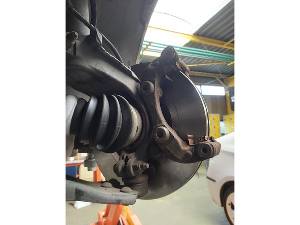 Retirez l'étrier de frein. Recommander :Attachez l'étrier à la suspension ou à la caisse à l'aide d'un fil de fer, sans débrancher le flexible de frein afin d'éviter la dépressurisation du système. Assurer vous que l'étrier de frein n'est pas accroché sur le flexible de frein. N'appuyez pas sur la pédale de frein après le retrait de l'étrier frein.