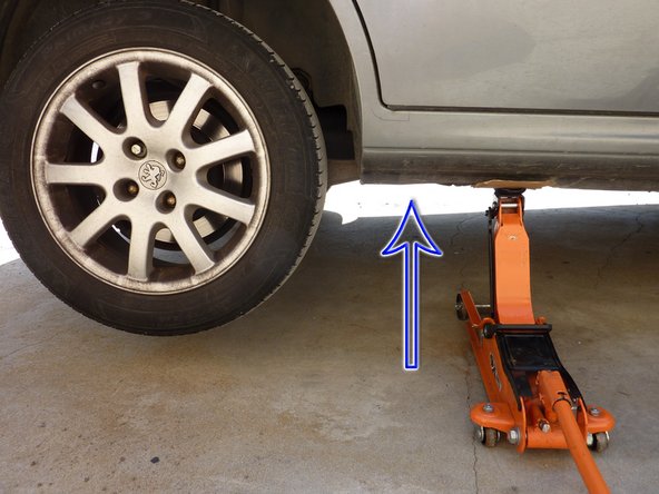 placer le cric au niveau du point de levage et procéder à la levée de la voiture (flèche bleu).