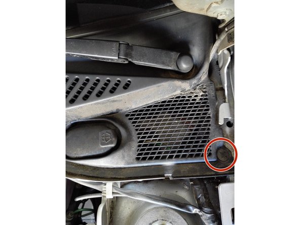 A l'aide d'un tournevis plat, soulever délicatement le clip entouré en rouge. Ce clip fixe la grille en plastique à la carrosserie.