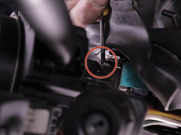 Relever les languettes de guidage du comodo à l'aide d'un tournevis plat et tirer dessus pour le retirer