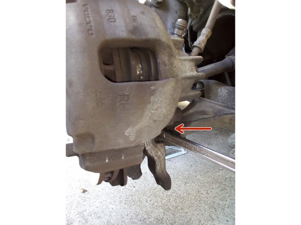 Dévissez les deux vis de la patte de fixation inférieure derrière l'étrier à l'aide d'une clé de 15.