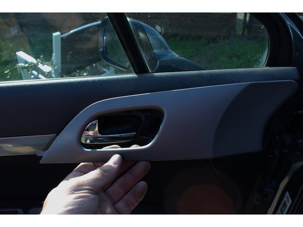 Dé-clipser l'enjoliveur de la pognée de porte en effectuant un effet de levier avec un tournevis plat en commençant par le bas puis le tirer délicatement vers l'intérieur de la voiture.