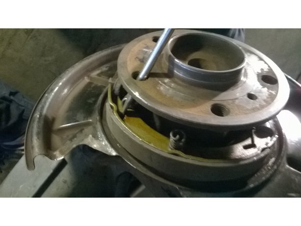 Décrocher le ressort de rappel inférieur en utilisant un gros tournevis plat. Laisser le levier d'écartement en place.