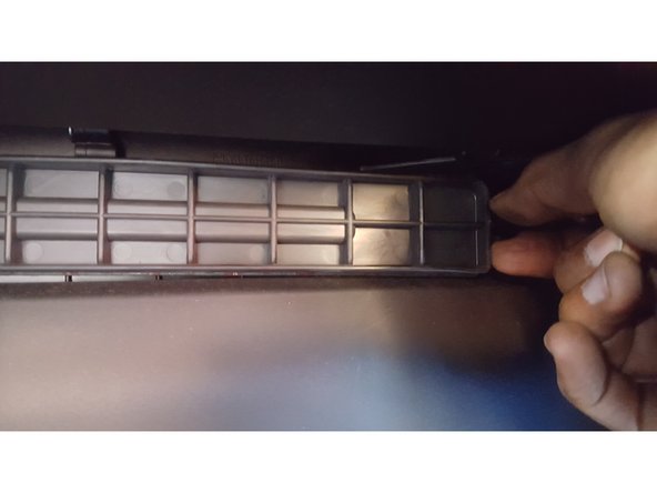 Les deux ergots sur la partie droite de la plaque doivent êtres pincés et ainsi  ça libèrera la partie droite, ensuite il faut glisser légèrement la plaque sur la droite afin de libérer complètement la plaque en plastique