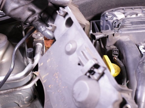 Retirer le carter inférieur en plastique par le haut en dégageant l’accès des tuyaux de climatisation et de la durite d'essence