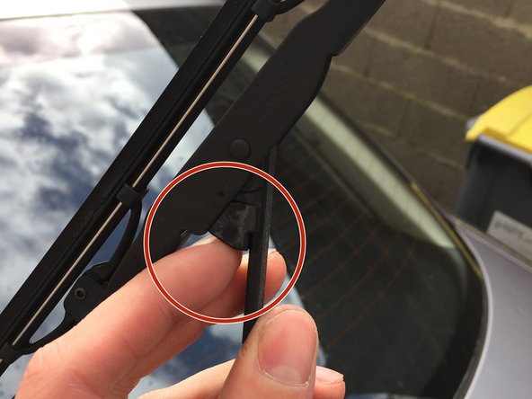 Appuyez sur la languette située en dessous du balais (flèche)