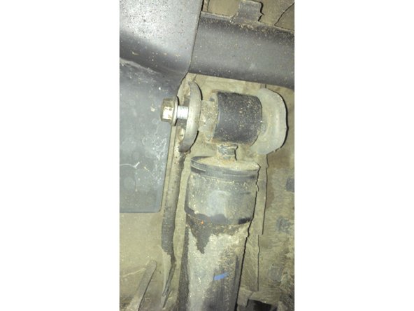 Soulevez la coupelle du ressort à l'aide du cric (3cm environ) et commencer à dévisser en haut et en bas (clé à cliquet douille de 18). Retirez la vis en haut puis en bas.