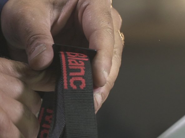 Rentre la sangle dans le premier trou de la boucle puis la faire ressortir par le second trou