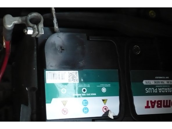 Baissez-vous et gardez le dos droit pour saisir la nouvelle batterie par ses poignées et placez la dans le compartiment moteur.