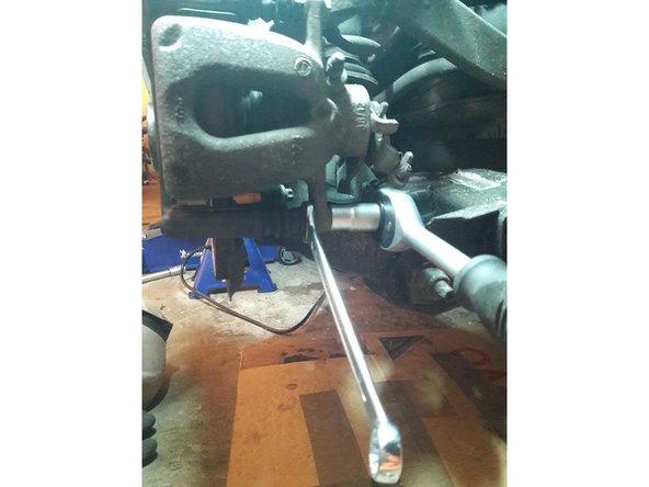 Il faut maintenir la clé plate 15 afin que que l'axe ne tourne pas et dévisser avec la clé 13