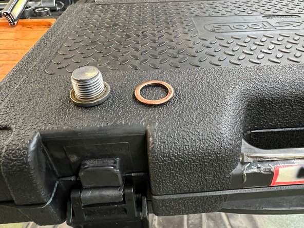 on passe maintenant a la vidange on prend un gros cliquet et une douille adapté pour ouvrir mais il faut le faire lentement pour éviter les éclaboussure puis on nettoie la vis de vis de vidange et on change le joint de la vis et puis on le revisse en regardant bien si ces bien plaqué et étanche