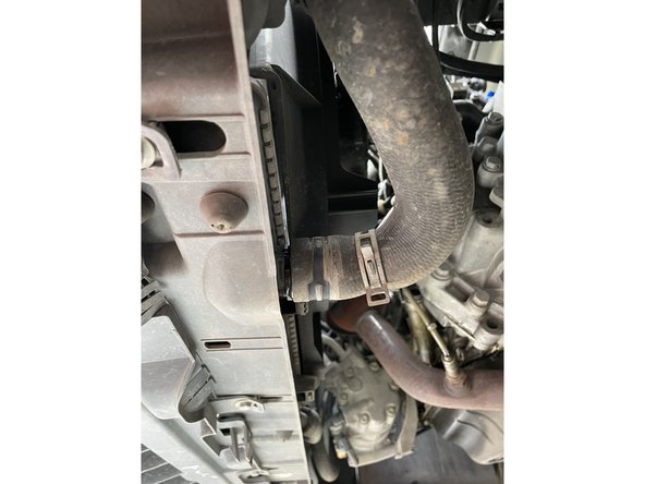 Je desserre le collier de serrage et place le bac de récupération dessous, puis je retire prudemment la durite afin de laisser couler le liquide.