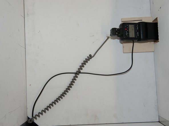 Blitz auf oberem Tablar positionieren. Kabel durch Ausspaarung nach unten ziehen.