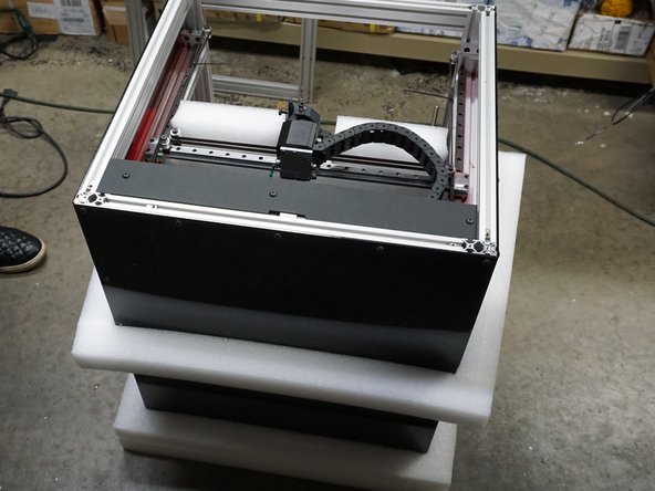 With one person on opposite sides of the box. Each person should grab the top aluminum with one hand and the top of the box with the other.