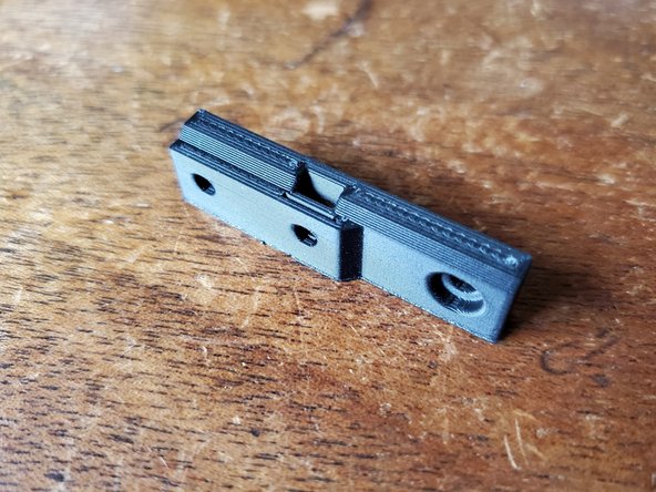 Locate the layer fan adapter (In this kits this part is white, not black as shown), and insert an M3 nut into the slot on it as shown.