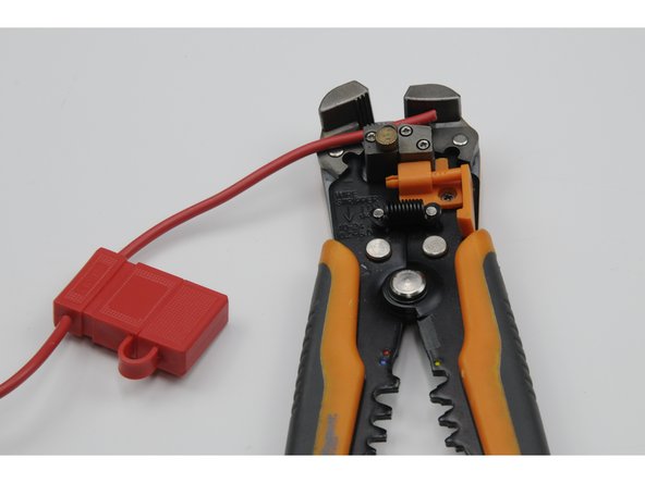 Using your wire strippers, strip 15mm from the ends of the red fuse wire and the red power wire.