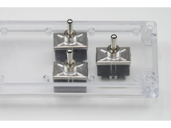 The black box of the switch should be inside the control box, the toggle switch should stick up through the holes in the clear plastic faceplate.