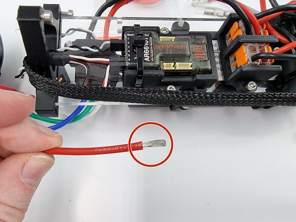 Grab the red power wire and strip the insulation from the end of the wire.