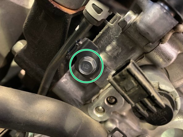 Remove the upper 10mm bolt holding the hardline next to the oil control solenoid pigtail electrical wiring clip unplugged in the previous step