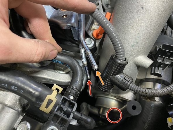 Install the short silicone hose onto the small bent metal pipe (red arrow)