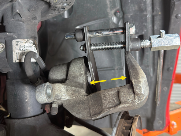 Using a C-clamp or a caliper compressing tool as shown, compress the caliper piston enough for the caliper to slide over the new pads