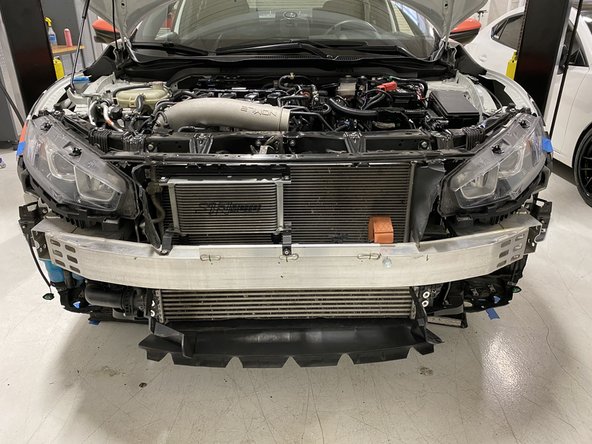 Reach between the bumper and the rest of the vehicle. Unplug the fog light by squeezing the top  and bottom of the plug