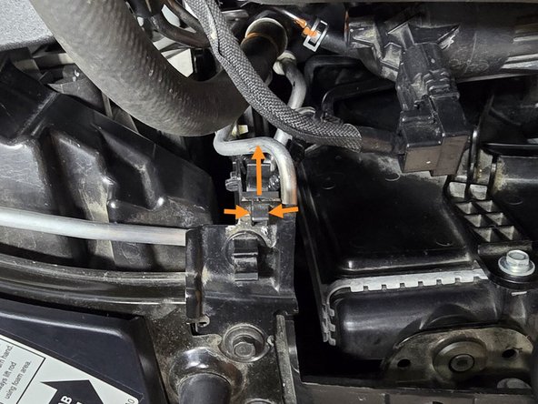 Optional: Using your fingers, or a pair of needle nose pliers, press in the two plastic tabs shown and remove the OE line clip as shown