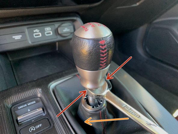 While holding the shift knob, use a 14mm wrench to loosen the locking nut