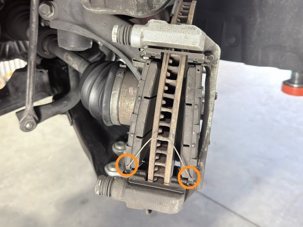 Align the brake pad retaining clip in each brake pad and reinstall as shown