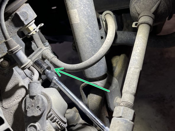 Using 12mm socket on extension, remove the brake line bracket on the caliper