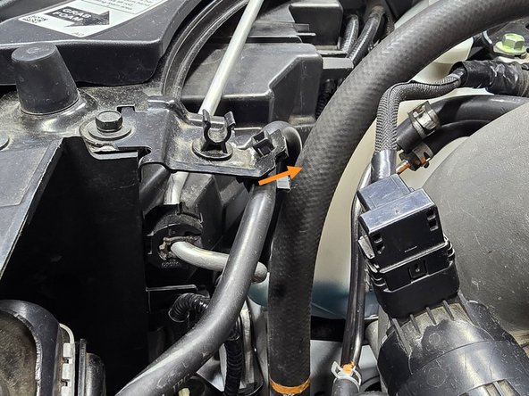 Use your hand to pull the OE coolant line out of the plastic clip as shown