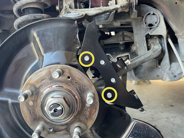 Hand thread the caliper bracket retaining bolt as shown