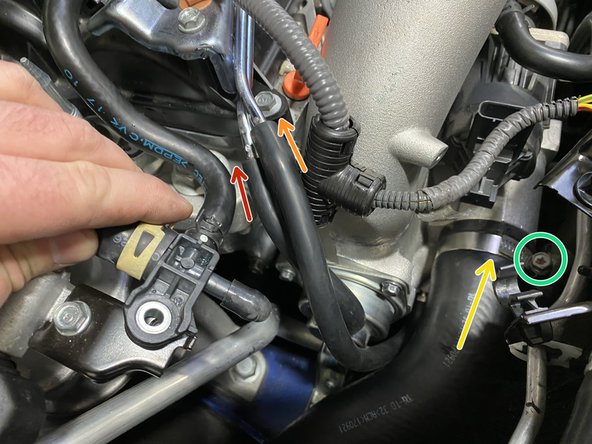 Install the long silicone hose onto the large bent metal pipe (orange arrow)