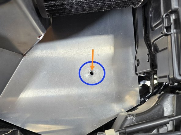 Moving the lower bracket, align the hole on the bracket with the hole in the bottom of the shroud as shown