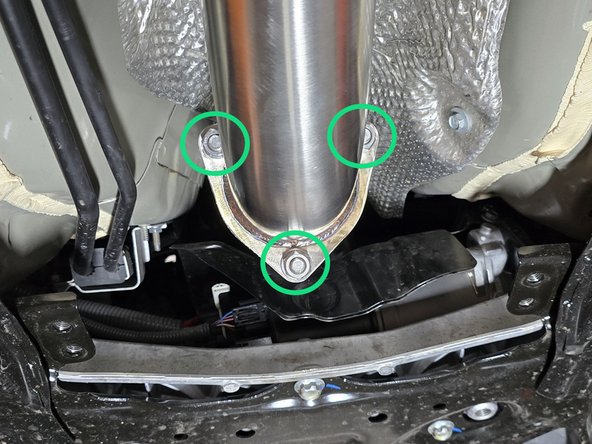 Using a 6 inch extension, and a 17mm socket tighten down the hardware connecting the front pipe and mid pipe as shown