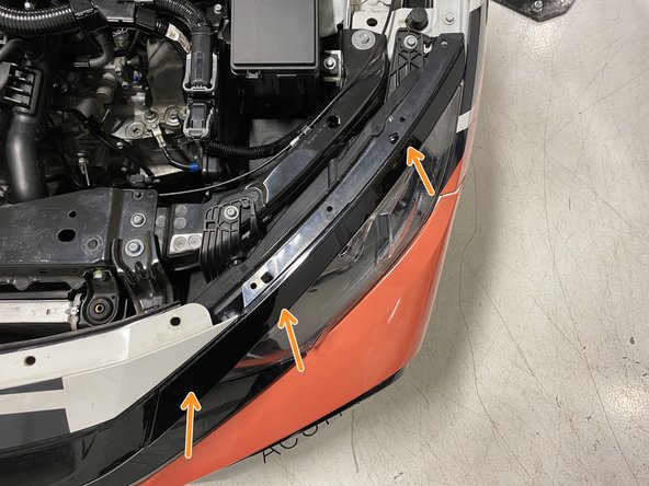 Position the upper headlight trim just above the headlight and gently push it inward to connect the two clips to the headlight