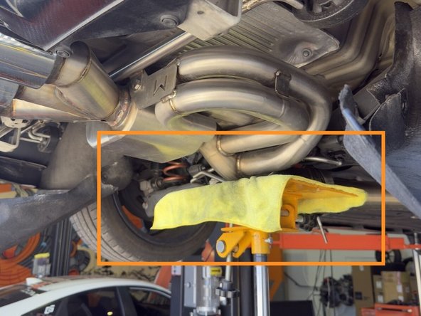 Support muffler section with a transmission jack as shown here. If working without a lift, support muffler section with something sturdy to keep it from falling to the ground when the hangers are removed next