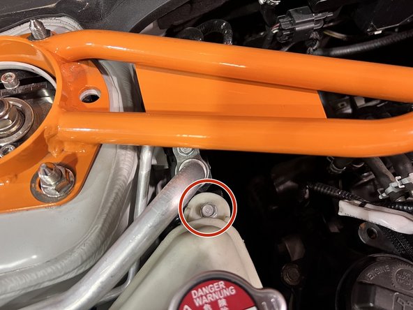 Use 10mm socket, ratchet, and extension to remove (2) 10mm bolts securing the coolant tank to its chassis brackets