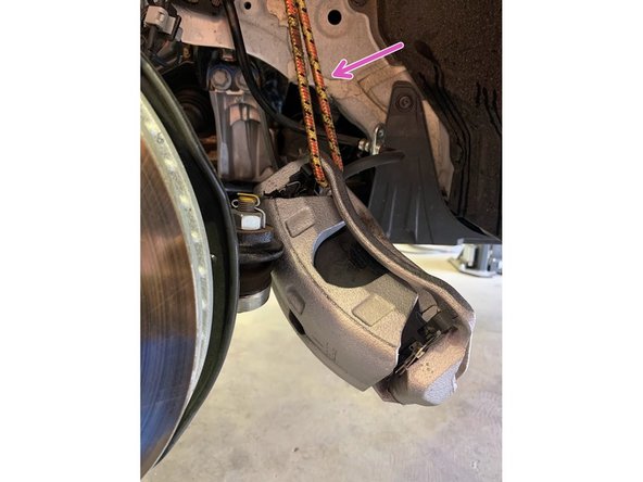 With the bolts removed, slide the brake caliper off the rotor in the direction of the orange arrow