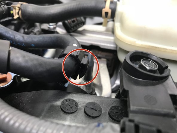 Reinstall the plastic clip holding the upper coolant hard lines and rubber hose